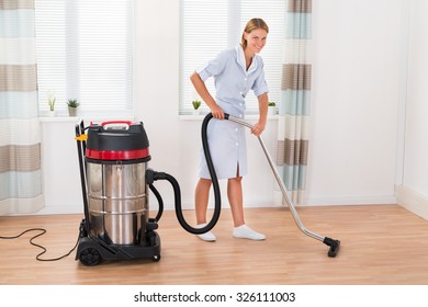Beautiful Female Maid Cleaning Wooden Floor With Vacuum Cleaner