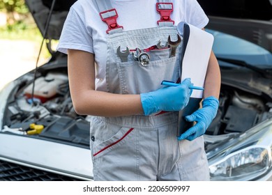 Beautiful Female Mechanic Is Working On A Car Breakdown At A Car Repair Shop. Woman Car Mechanic. Tools In The Hands Of A Woman