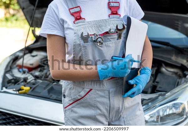 beautiful female mechanic is working on a car\
breakdown at a car repair shop. woman car mechanic. tools in the\
hands of a woman