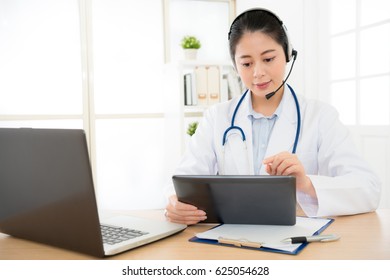 Beautiful Female Medicine Doctor Explain Diagnosis To Patient By Online System App And Holding Digital Tablet Pc Touching Screen Typing Text On The Files.