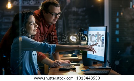 Beautiful Female Mobile Gaming Application Developer Talks With Her Male Colleague, They Discuss Creative Design. Stylishly Lit Office.