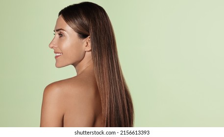 Beautiful female model, 40s years, has long healthy natural hair, shiny moisturized body after shower, portrait from behind, looking aside and smiling, green background - Shutterstock ID 2156613393