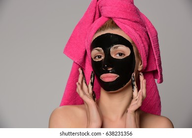 Beautiful Female Model With Black Facial Cosmetic Mask. Isolated On Gray Background