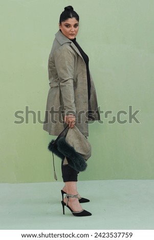 beautiful female model posing in green long coat leather jacket with stylish bun and hat