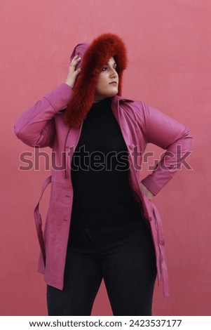 beautiful female model posing in pink leather long jacket with stylish red hat 