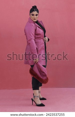 beautiful female model posing in pink leather long jacket with stylish red hat 