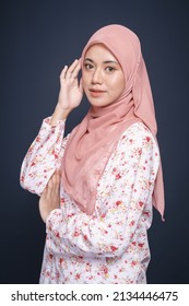Beautiful female model wearing modern "baju kurung" with hijab, an Asian traditional dress for Muslim woman isolated over dark background. Stylish Muslim female fashion lifestyle  concept.