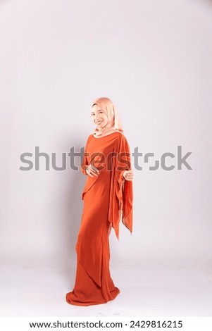 Beautiful female model wearing modern kurung, an Asian traditional dress for Muslim woman isolated over grey background. Stylish Muslim female hijab fashion lifestyle portraiture concept.
