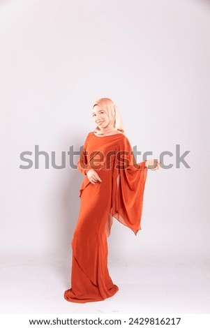 Beautiful female model wearing modern kurung, an Asian traditional dress for Muslim woman isolated over grey background. Stylish Muslim female hijab fashion lifestyle portraiture concept.