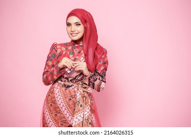 Beautiful female model wearing red batik kebaya with hijab, an Asian traditional dress for Muslim woman isolated over pink background. Stylish Muslim female fashion lifestyle  concept. - Powered by Shutterstock