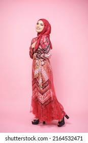 Beautiful female model wearing red batik kebaya with hijab, an Asian traditional dress for Muslim woman isolated over pink background. Stylish Muslim female fashion lifestyle  concept.