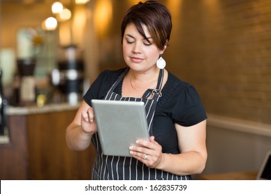 Beautiful Female Owner Using Digital Tablet In Cafe