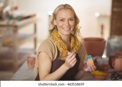 Beautiful female potter painting on bowl in pottery workshop - Powered by Shutterstock