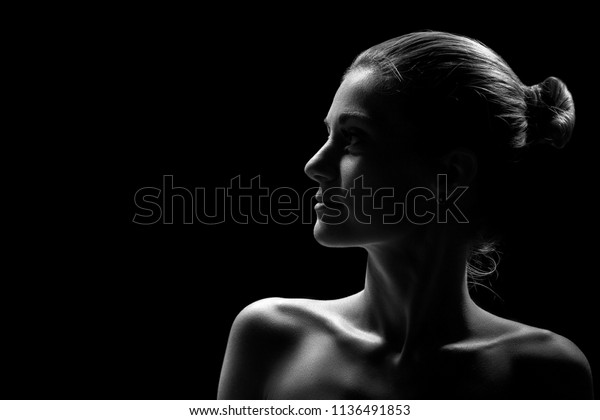 beautiful female profile with bare\
shoulders on black background with copy space,\
monochrome