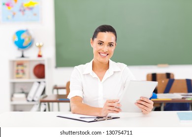 Beautiful Female School Teacher Holding A Tablet Computer In Classroom