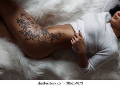 Beautiful female sexy body with a stylish vintage tattoo on thigh. 