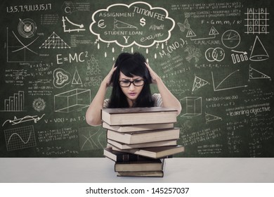 Beautiful female stressing out due to exam with pile of books in class