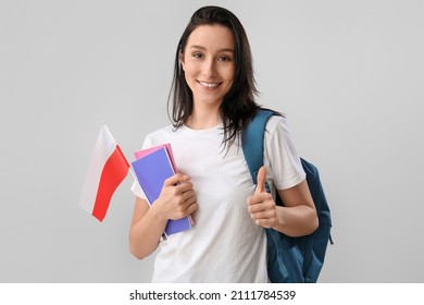 Beautiful female student with flag of Poland showing thumb-up on light background