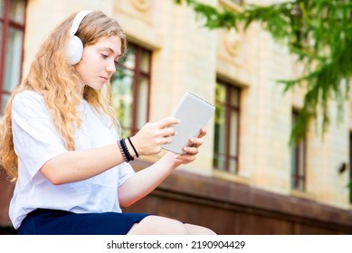 Beautiful Female Student Watching Online Lecture Through Tablet, Studying Online. Listening To Music, Watching A Movie Outside