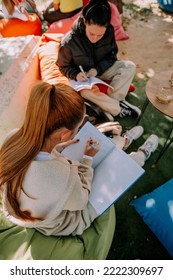 Beautiful Female Students Are Sitting On A Lazy Bags In A Coffee Bar And Studying Together For The Next Exam