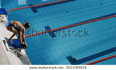 Beautiful Female Swimmer Diving in Swimming Pool. Professional Athlete Standing on a Starting Block, Ready to Jump into Water. Person Determined to Win Championship. High Angle view.