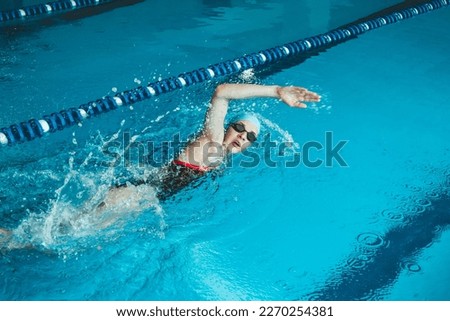 Beautiful female swimmer using front bypass, freestyle in the pool. Preparing professional athletes to win the championship
