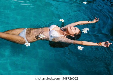 Beautiful female in swimming pool background with white Spa flowers