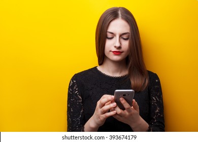 Beautiful Female User Mobile Phones On A Yellow Background. Dependence On Smartphone