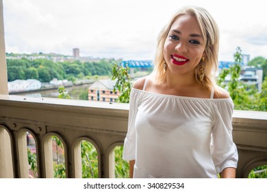 Beautiful female woman with blonde hair, and red lipstick.  She is smiling, and stood on the High level bridge, Newcastle Upon Tyne.