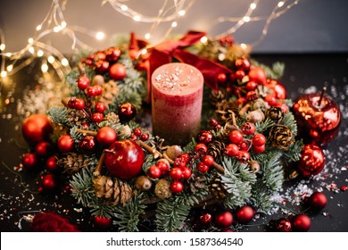 Beautiful festive hand made wreath decorated with fresh nobilis spruce, red ornaments, berries, pine cones, candle, acorns, fake snow, decorative apples, glitter with fireflies on the background,  - Powered by Shutterstock