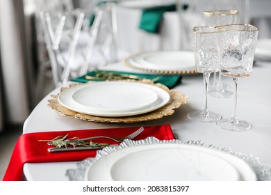 Beautiful Festive Table Setting With Napkins Of Different Colors. A Luxurious Dining Set With Cutlery, Napkin, Dishes And Covered With A Tablecloth In The Restaurant. Gold Plates And Crystal Glasses. 