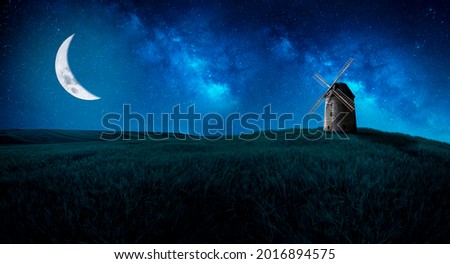 A beautiful field at night with a wonderful waning moon and a simple mill.
