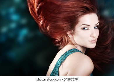 A Beautiful Fiery Red Haired Woman With Her Hair Mid Movement With A Blue Abstract Background.