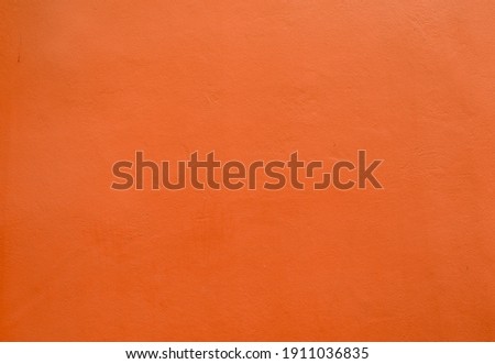 Beautiful fiery red-orange wall grunge cement, abstract texture. Orange color fun, warmth, fire, energy. Orange autumn hues degrade background vivid light top, dark bottom. Halloween background empty.
