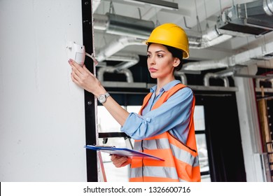 Beautiful Firefighter Checking Fire Alarm While Holding Clipboard