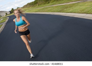 A Beautiful Fit And Healthy Blond Woman Road Running While Listening To Music On Her Portable Mp3 Player