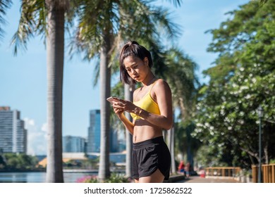 Beautiful fit sport woman looking at mobile phone internet app tracking performance after running workout stock photo