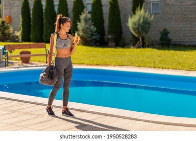 Beautiful Fit Young Woman In Sports Clothes Carrying Gym Bag And Eating A Banana Before An Outdoor Workout