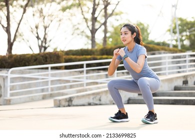 Beautiful Fitness Asian Woman Doing Squat Sit Up Exercise Workout At Sport Stadium. Attractive Female Warming Up Body Training Wearing Sportswear. Healthy And Active Lifestyle Concept.