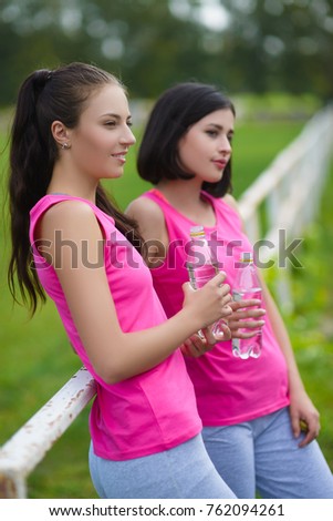 Beautiful fitness athlete girls resting or drinking water outdoor