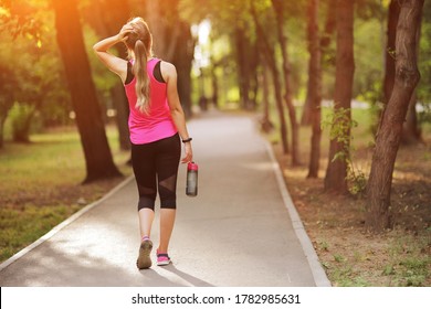 Beautiful fitness athlete runner woman drinking water in the park. Water bottle