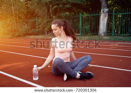 Beautiful fitness athlete woman drinking water after work out exercising 