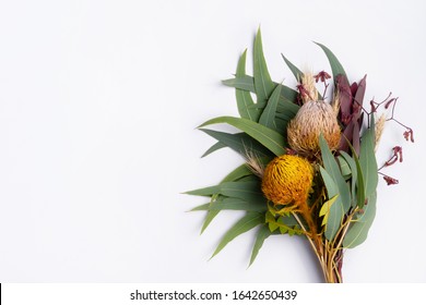 Beautiful Flat Lay Floral Arrangement Of Mostly Australian Native Flowers, Including Protea, Banksia, Kangaroo Paw, Eucalyptus Leaves And Gum Nuts On A White Background. 