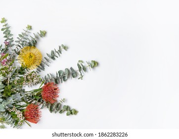 Beautiful Flat Lay Floral Border Or Framing Arrangement Of Mostly Australian Native Flowers, Including Red And Yellow Waratahs,  Eucalyptus Leaves And Wax Flowers, On White Background. Space For Copy.