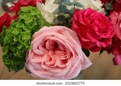 A beautiful floral arrangement featuring a soft pink rose, vibrant red roses, fresh green leaves, and delicate white hydrangeas, highlighting nature’s vibrant colors and elegance. - Powered by Shutterstock