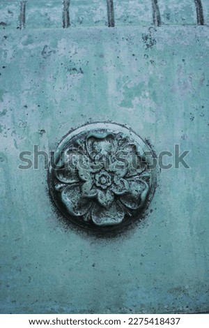 A beautiful floral medallion sculpture in a copper metal wall with lots of green patina.