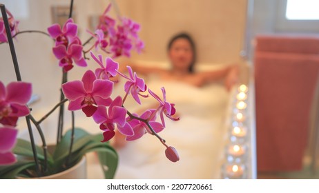 Beautiful flowering orchid with pretty young lady relaxing in nice bubble bath. Beautiful young woman enjoying and relaxing in bathtub. Tranquil and pleasant atmosphere for spa treatment experience. - Shutterstock ID 2207720661