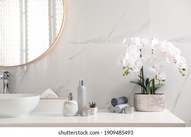 Beautiful flowers, burning candles and different toiletries on countertop in bathroom