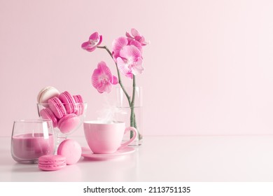 Beautiful flowers composition with pink orchid flower, steaming cup coffee or hot drink and macaroon on pastel pink background. Valentine's day, Happy women's day