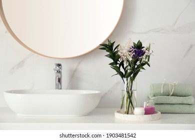 Beautiful flowers, towels and candle on countertop in bathroom. Interior decor